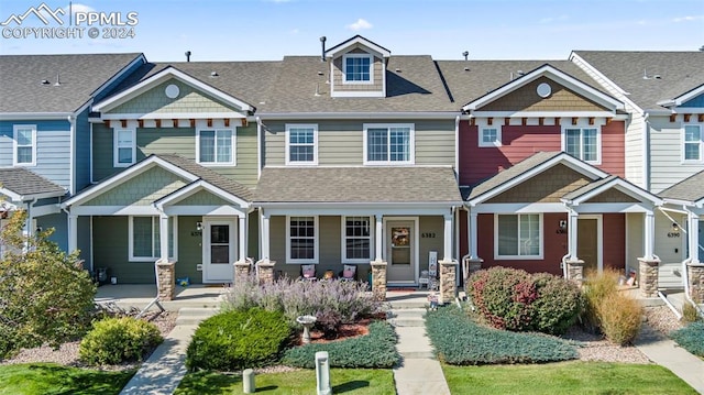 townhome / multi-family property featuring covered porch and a shingled roof