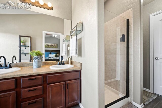 ensuite bathroom featuring double vanity, a stall shower, and a sink