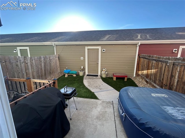 back of house with a shingled roof, a patio area, and fence