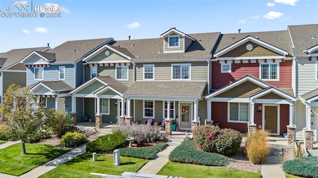 view of property with a shingled roof, a residential view, a front lawn, and a porch