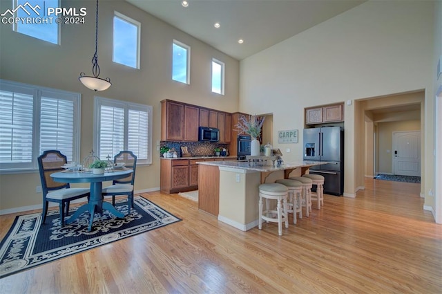 kitchen featuring decorative light fixtures, backsplash, a kitchen island, a towering ceiling, and high quality fridge