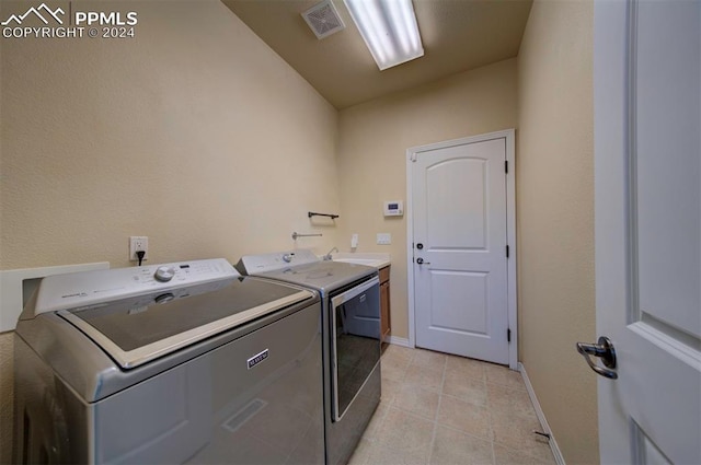 laundry area featuring cabinets, light tile patterned flooring, and independent washer and dryer