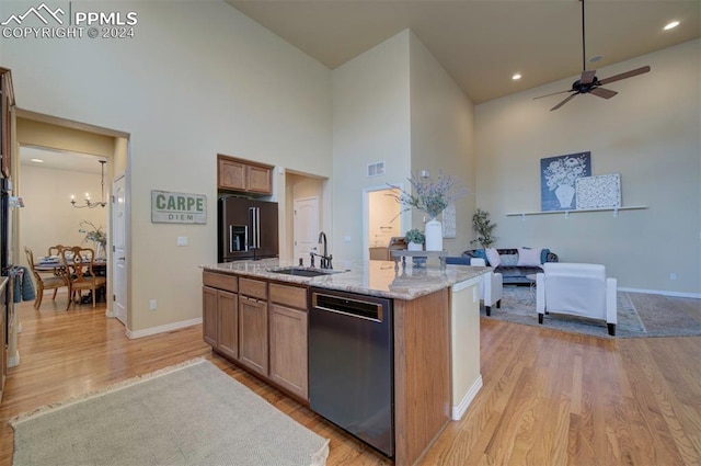 kitchen with light hardwood / wood-style floors, a center island with sink, a towering ceiling, sink, and stainless steel appliances