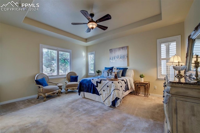 bedroom featuring ceiling fan, light colored carpet, and a raised ceiling