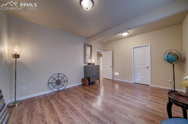 bedroom with hardwood / wood-style floors and beamed ceiling