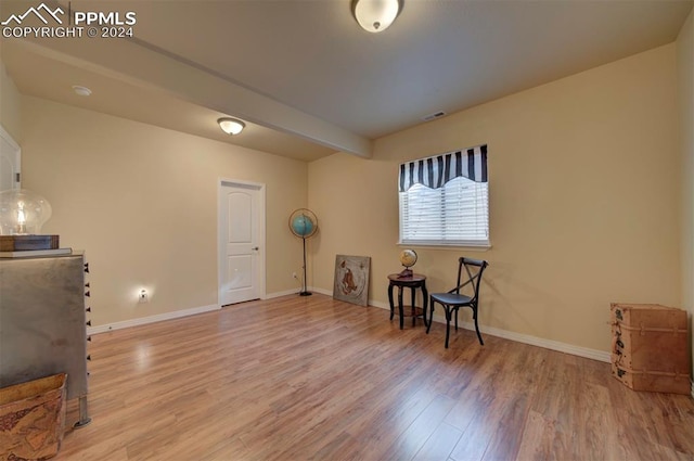 living area featuring beamed ceiling and hardwood / wood-style flooring