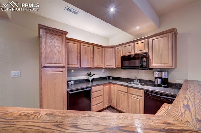 kitchen featuring sink, dark stone counters, and black appliances