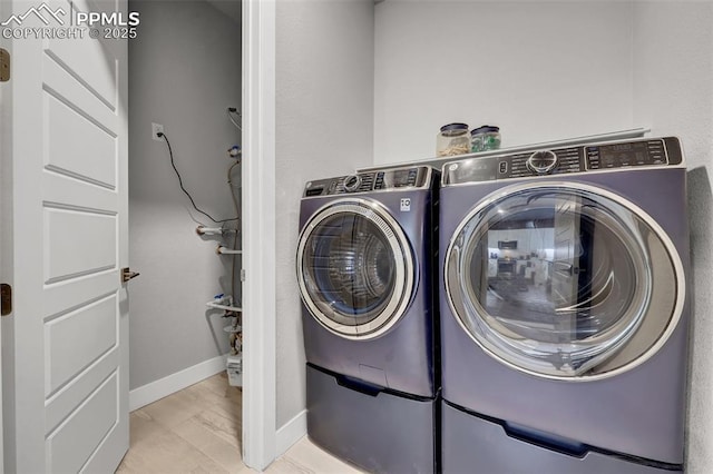 clothes washing area with separate washer and dryer, laundry area, and baseboards
