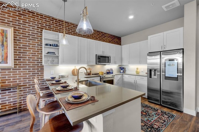 kitchen with hanging light fixtures, stainless steel appliances, a sink, white cabinetry, and a peninsula