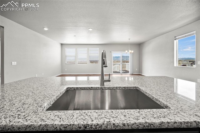 kitchen with sink, light stone counters, and a healthy amount of sunlight