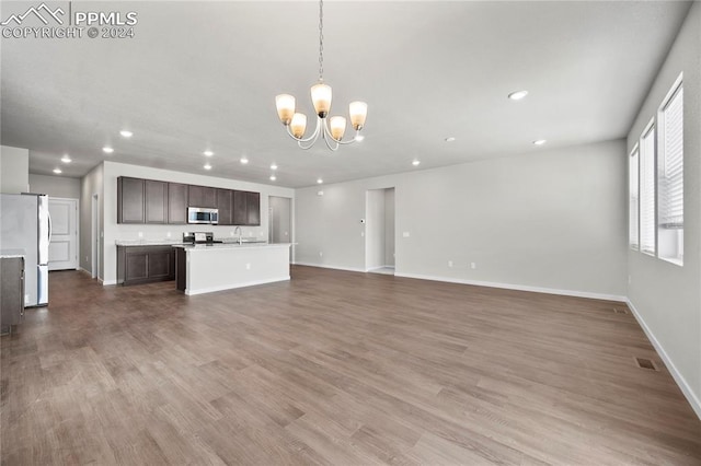 unfurnished living room with hardwood / wood-style flooring and a notable chandelier