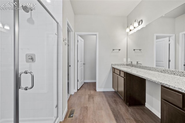 bathroom with vanity, hardwood / wood-style floors, and a shower with door