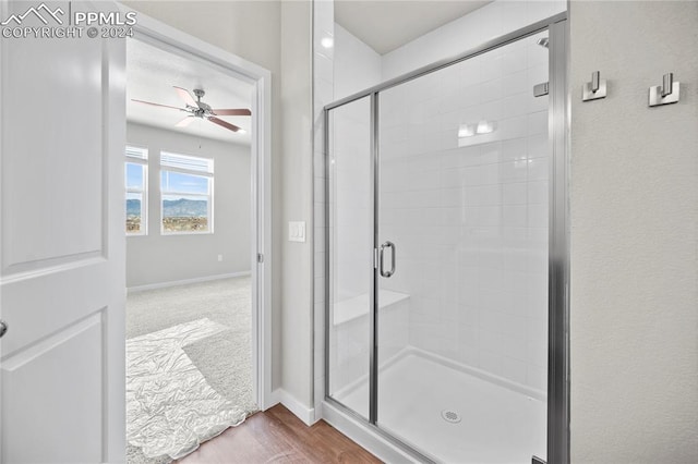 bathroom with ceiling fan, hardwood / wood-style floors, and a shower with shower door