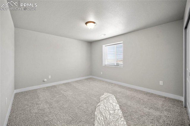 carpeted empty room featuring a textured ceiling