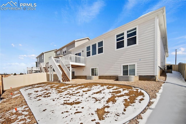 snow covered house featuring a wooden deck