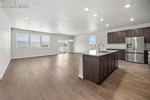 kitchen featuring a kitchen island with sink, hardwood / wood-style floors, stainless steel appliances, sink, and dark brown cabinets