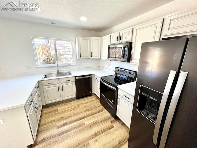 kitchen featuring light wood-type flooring, stainless steel appliances, white cabinets, sink, and a textured ceiling