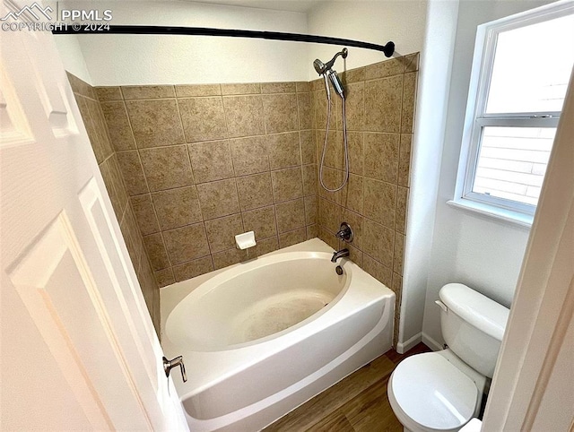 bathroom featuring hardwood / wood-style flooring, toilet, and tiled shower / bath combo