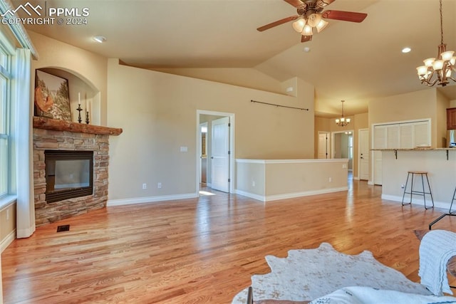 living room featuring light hardwood / wood-style floors, lofted ceiling, ceiling fan with notable chandelier, and a fireplace