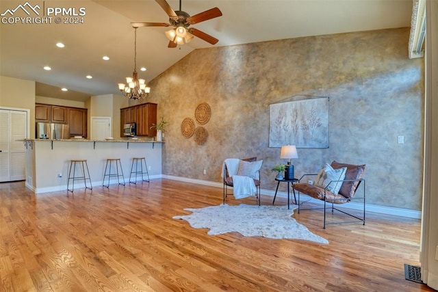 unfurnished room with light hardwood / wood-style floors, high vaulted ceiling, and ceiling fan with notable chandelier