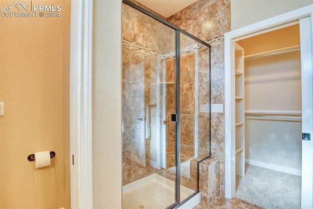 bathroom with a shower with shower door and tile patterned flooring