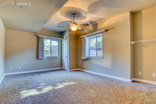 carpeted empty room featuring a wealth of natural light, a textured ceiling, and ceiling fan