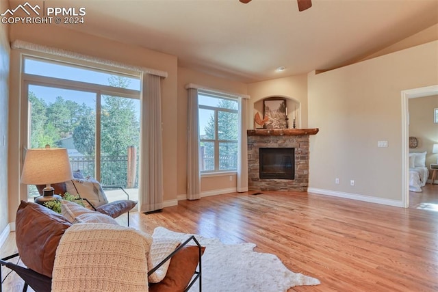 living room with a fireplace, light wood-type flooring, and ceiling fan