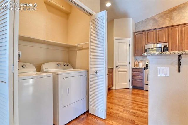 clothes washing area with light hardwood / wood-style floors and washer and clothes dryer