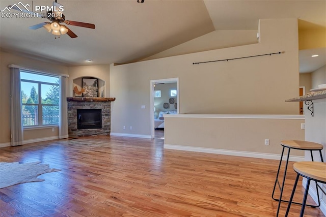 unfurnished living room featuring a fireplace, ceiling fan, light wood-type flooring, and vaulted ceiling