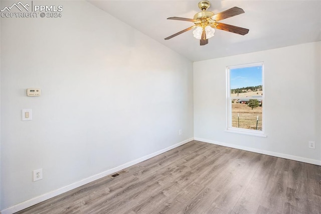spare room featuring visible vents, wood finished floors, baseboards, a ceiling fan, and vaulted ceiling