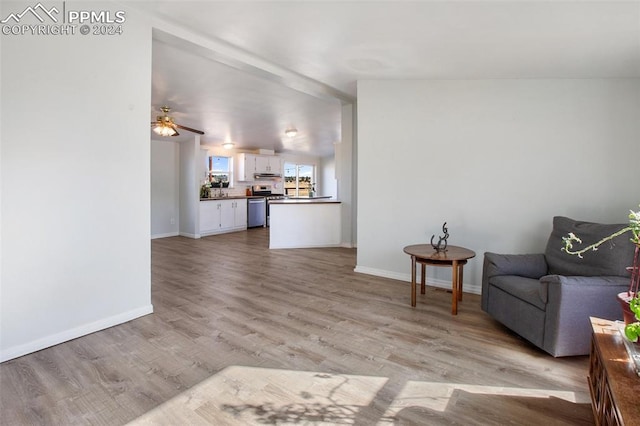living area featuring baseboards, a ceiling fan, and light wood finished floors