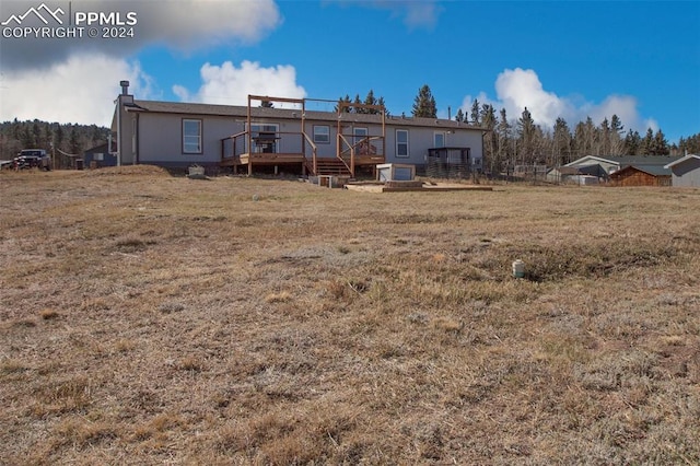 back of property with a deck and a lawn