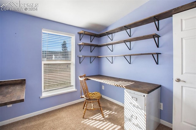 office area featuring baseboards, vaulted ceiling, carpet flooring, and built in desk