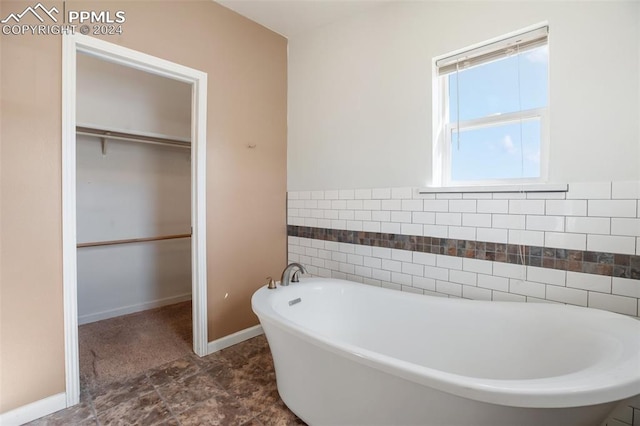 full bathroom with a walk in closet, a soaking tub, wainscoting, and tile walls