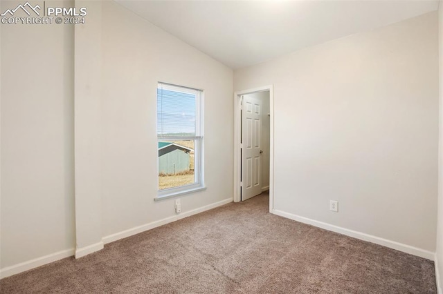 carpeted spare room with baseboards and vaulted ceiling