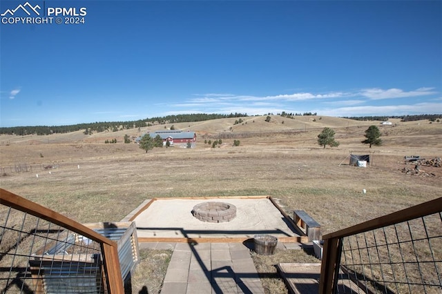 view of yard with an outdoor fire pit and a rural view