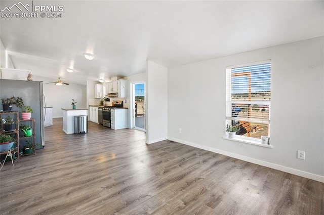 unfurnished living room with baseboards, a ceiling fan, and wood finished floors