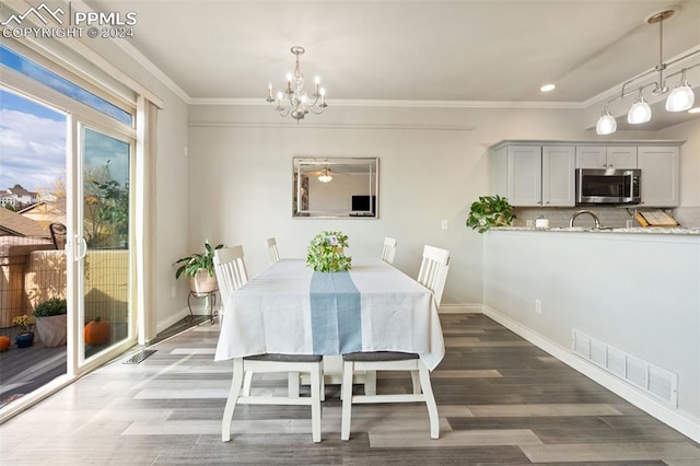 dining room with ceiling fan with notable chandelier, ornamental molding, and dark hardwood / wood-style flooring