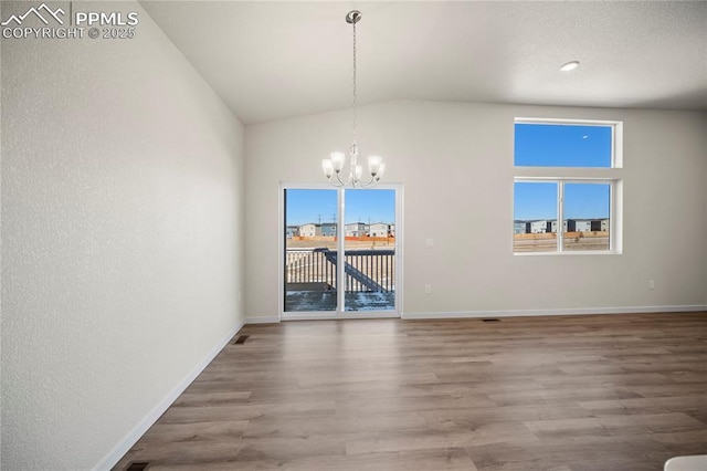 unfurnished dining area featuring lofted ceiling, plenty of natural light, wood finished floors, and a notable chandelier