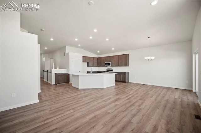 kitchen with stainless steel appliances, pendant lighting, light countertops, and open floor plan