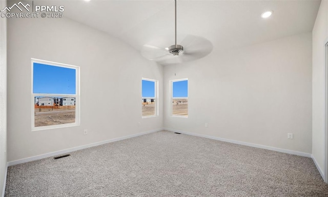 carpeted spare room with lofted ceiling, visible vents, ceiling fan, and baseboards