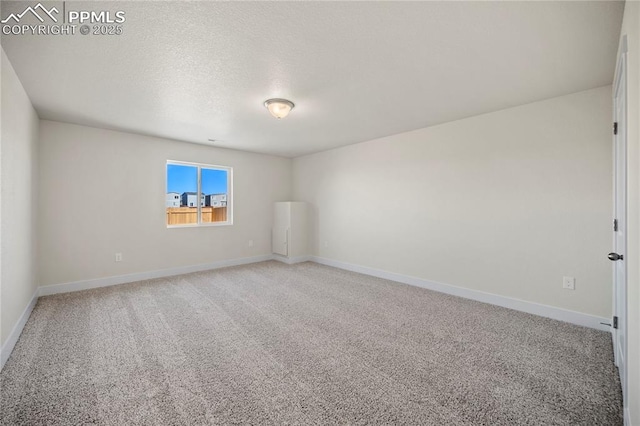 carpeted spare room featuring baseboards and a textured ceiling