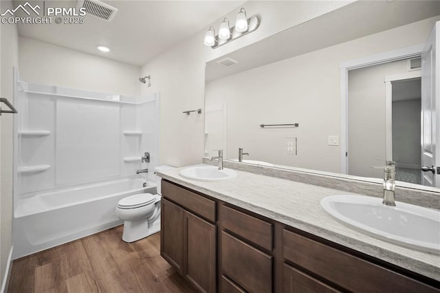 bathroom with shower / bath combination, a sink, visible vents, and wood finished floors