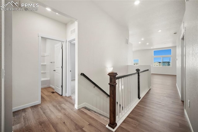 corridor with visible vents, baseboards, an upstairs landing, light wood-style floors, and recessed lighting