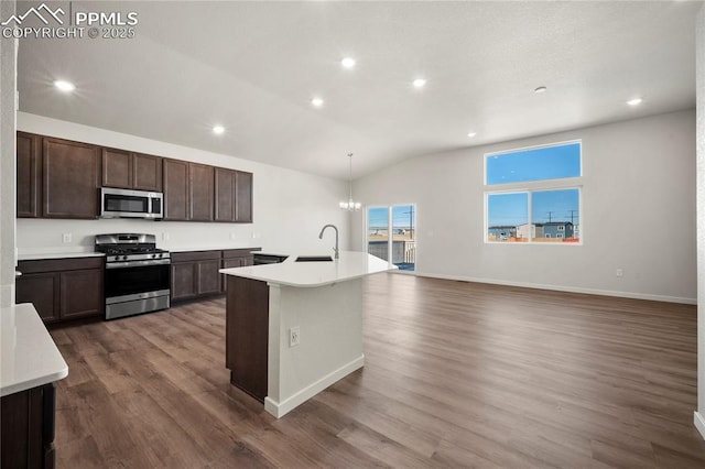 kitchen with decorative light fixtures, a sink, light countertops, appliances with stainless steel finishes, and a center island with sink