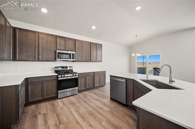 kitchen featuring light countertops, appliances with stainless steel finishes, a sink, and decorative light fixtures