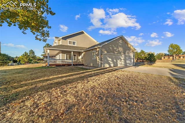 rear view of property with a lawn, a garage, and a porch