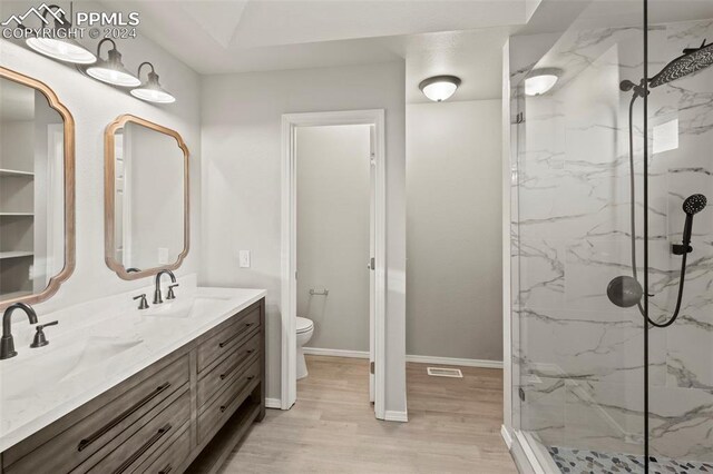 6555 Turkey Tracks Rd, Colorado Springs, CO 80922 - bathroom with toilet, wood finished floors, a marble finish shower, and double vanity