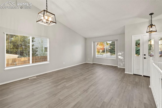 entrance foyer with lofted ceiling, a textured ceiling, a chandelier, and wood-type flooring