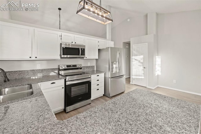 kitchen with sink, decorative light fixtures, white cabinetry, appliances with stainless steel finishes, and high vaulted ceiling